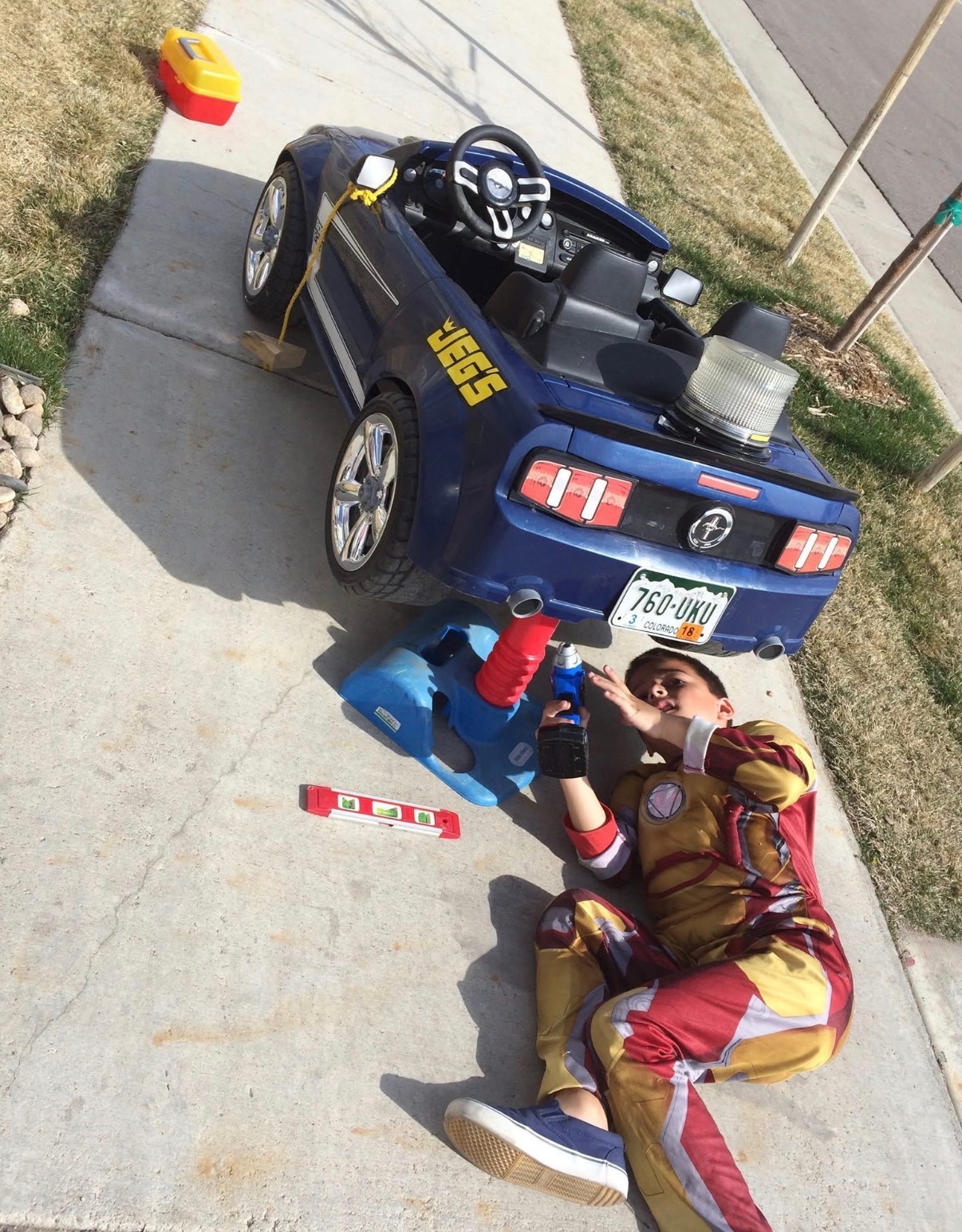 Little Maximus fixing his toy car in an Iron Man costume
