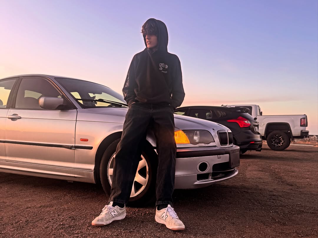 Maximus leaning on his BMW at sunset