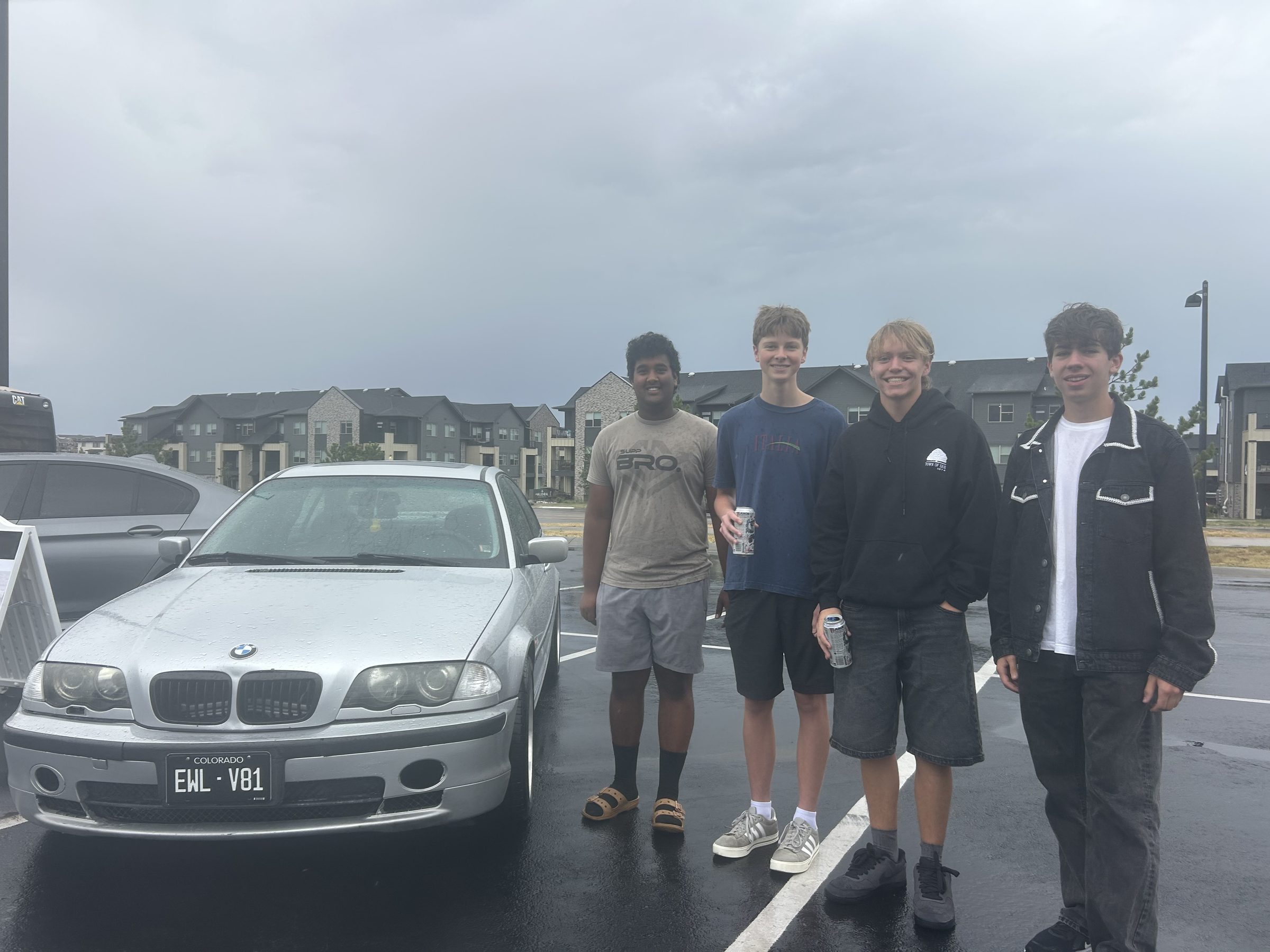 Maximus' friends standing beside his silver BMW